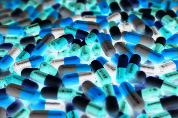 Photo of Pile of blue, green, and white color of capsule pills with modern design light. Toxicology medicine concept. QC and QA in pharmaceutical industry background. Global healthcare.