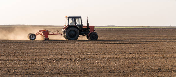 istock Farmer with tractor seeding  crops at agricultural field 1140104454