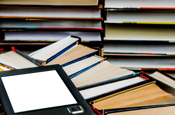 istock The e-book with a white screen lies on the open multi-colored books that lie on a dark background, close-up 1140105897
