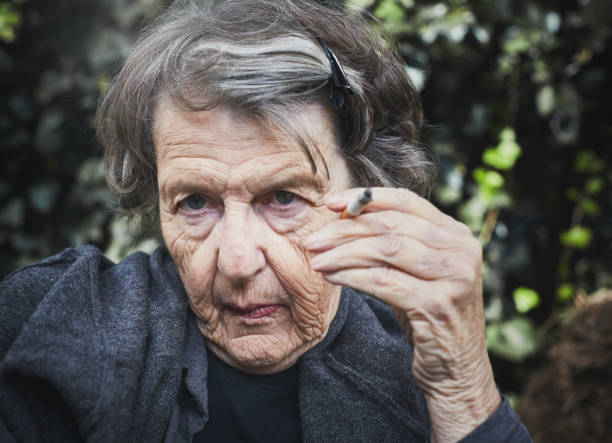 Wrinkled old woman shows effects of smoking A very wrinkled old woman holds a cigarette, still defiantly smoking despite the obvious damage done to her skin, as well as the rest of her body. smokers wrinkles stock pictures, royalty-free photos & images