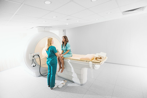 Young female patient preparing by technician to enter a mri scan.