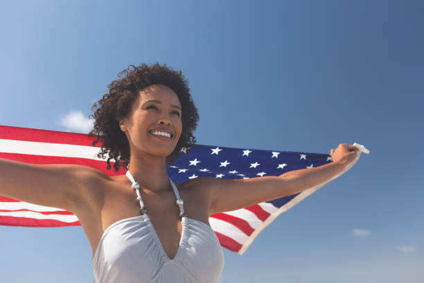 istock Woman holding american flag at beach 1140111370