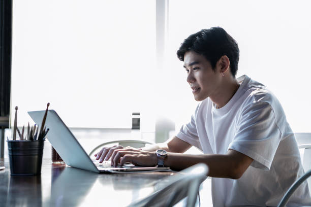 istock Young Asian Man Happily Working In The Office On His Laptop Computer 1140111618