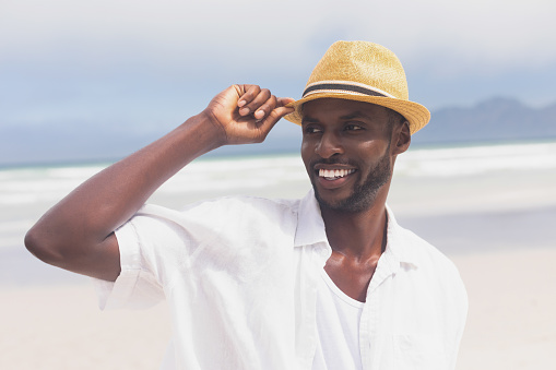 Portrait happy African American man standing at beach on a sunny day. He is smiling