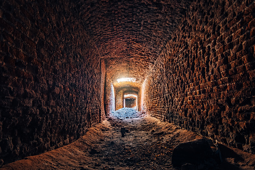 Old underground ruined red brick historical vaulted tunnel