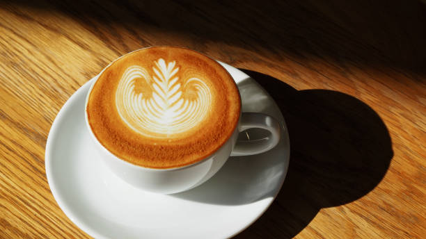 istock latte or Cappuccino art coffee cup top view on wood table with sunlight in cafe. 1140113349