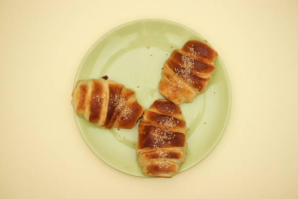 istock Croissant in green dish on yellow background 1140114060