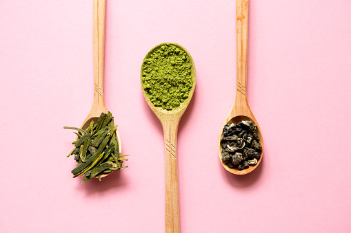 Biluochun, Matcha and Longjing. Chinese leaf and Japanese powdered green tea in a spoon on a pink background.