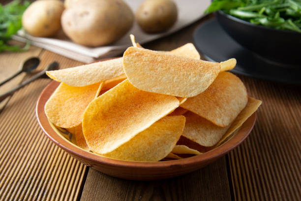 istock Potato chips in bowl and fresh potato. Delicious crispy snack. Rustic style. 1140115945