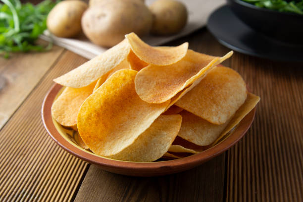 istock Potato chips in bowl and fresh potato. Delicious crispy snack. Rustic style. 1140115995