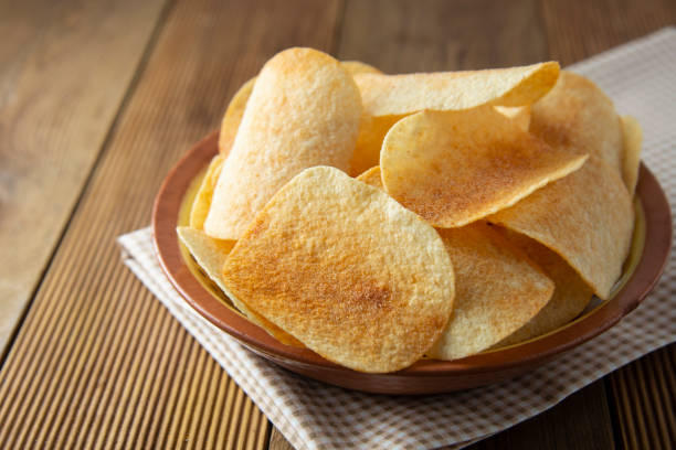 patatas fritas en cuenco y patata fresca. delicioso aperitivo crujiente. estilo rústico. - potatoe chips fotografías e imágenes de stock