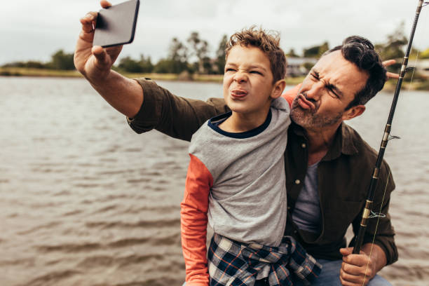 homme prenant le selfie avec son enfant à l’extérieur - fishing father son family photos et images de collection