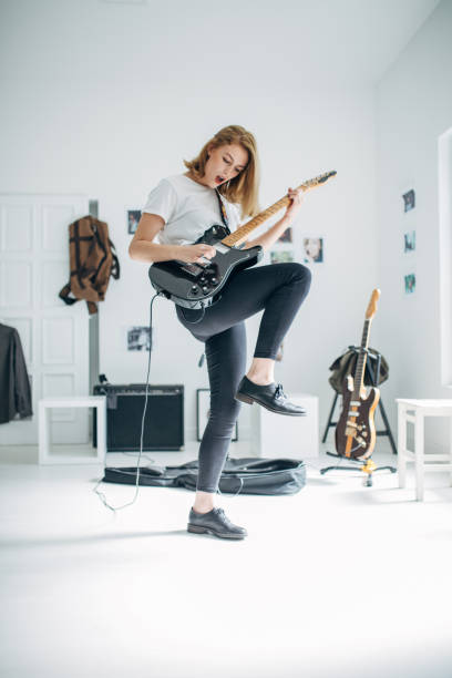 istock Young woman playing electric guitar in music studio 1140120710