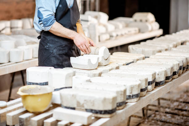 Male worker getting clay products from the gypsum forms at the pottery manufacturing, close-up view