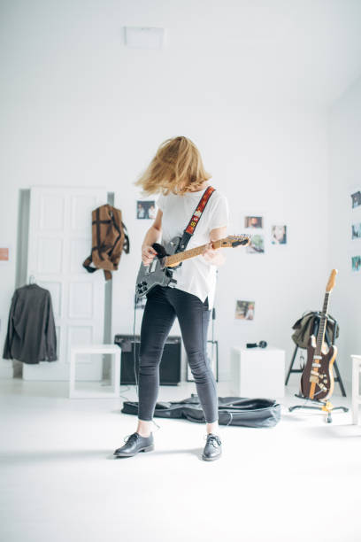 istock Young lady playing electric guitar in music studio 1140122467