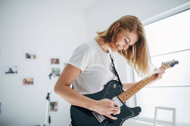 istock Charming woman playing guitar in music studio alone 1140124827