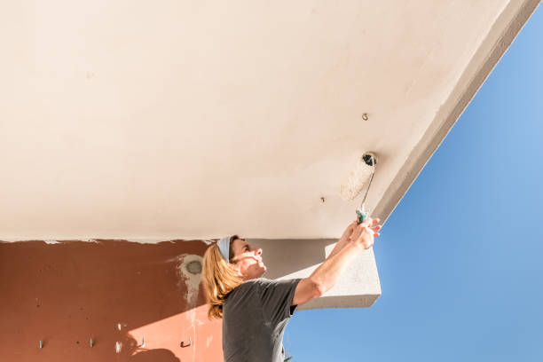 istock Low Angle View of Woman Painting Balcony Ceiling with Paint Roller 1140124949