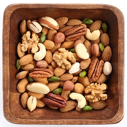 Different kinds of nuts in wooden bowl on a white background. Healthy food.