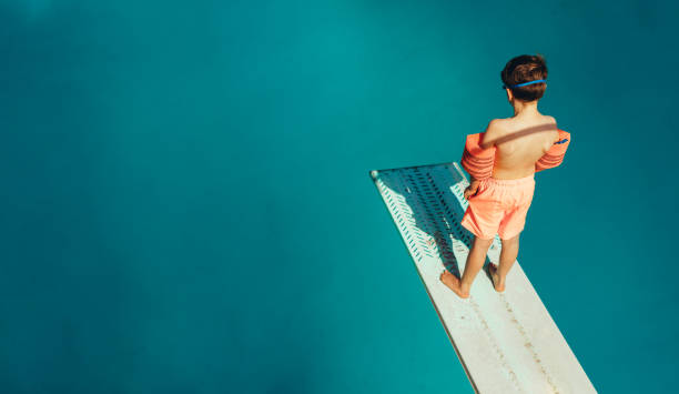 chico parado en un trampolín - diving board fotografías e imágenes de stock