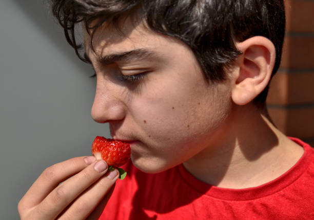 istock Caucasian child who is eating a strawberry 1140126763