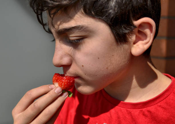 istock Caucasian child who is eating a strawberry 1140126765