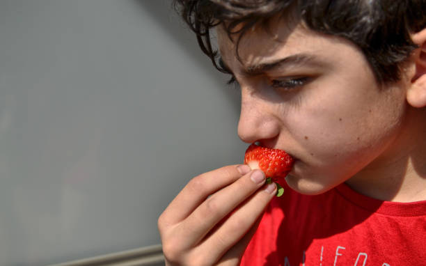 istock Caucasian child who is eating a strawberry 1140126766