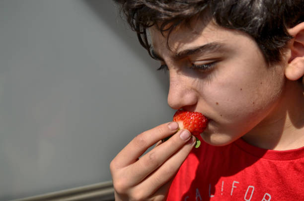 istock Caucasian child who is eating a strawberry 1140126780