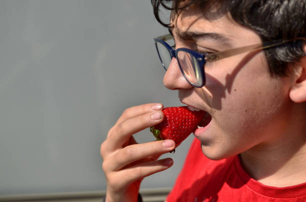 istock Caucasian child who is eating a strawberry 1140126832