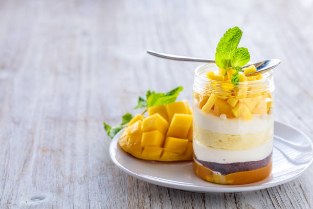 Sweet homemade Mango dessert, cheesecake, trifle, mouse in a glass jar on a light wooden background stock photo