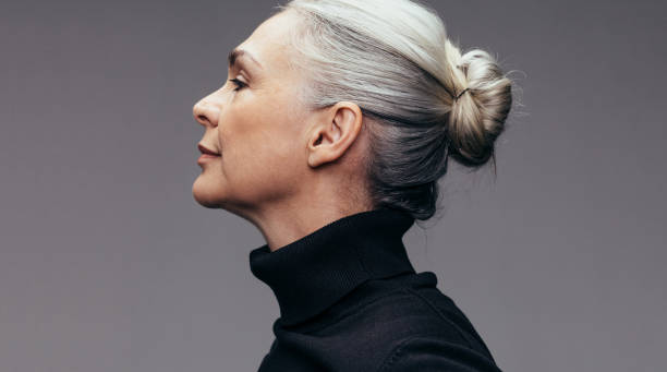 donna anziana su sfondo grigio - gray hair immagine foto e immagini stock