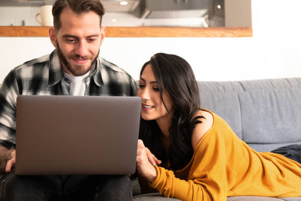 istock Happy couple relaxing on sofa with laptop 1140128366