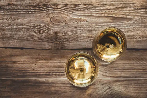 Two glasses of white wine on the wooden background