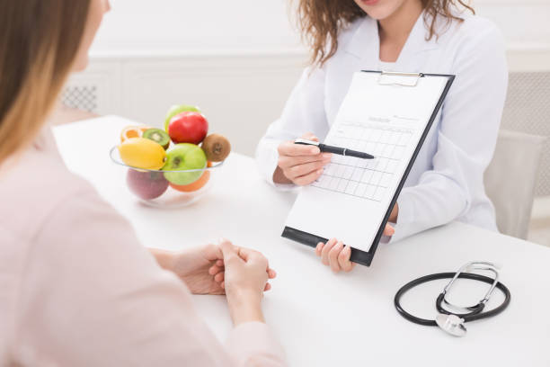 Healthy nutrition expert making weekly meal plan for client Food coaching. Professional dietitian explaining meal plan to patient at consultation mass unit of measurement photos stock pictures, royalty-free photos & images