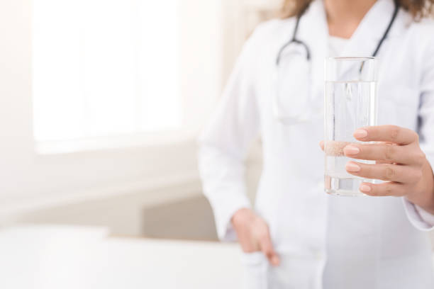 Doctor holding glass of clear fresh water Therapist holding glass of clear fresh water. Doctor recommend drinking healthy aqua, empty space fast water stock pictures, royalty-free photos & images