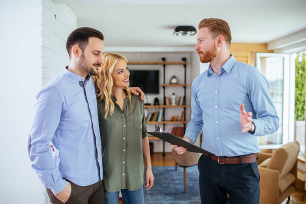 Making responsible decisions about their future Photo of a young couple counseling with financial adviser at home. salesman photos stock pictures, royalty-free photos & images