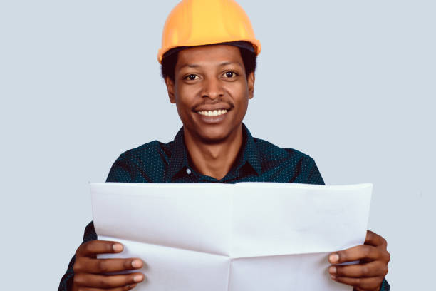 istock Afro american architect in hard hat with blueprint. 1140135585