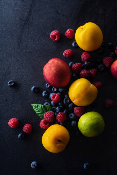 istock Creative flatlay with fresh fruits and berries on dark background. Grapes, blueberries, raspberries with peaches and lime 1140137931