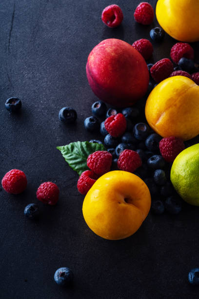 istock Creative flatlay with fresh fruits and berries on dark background with copy space. Grapes, blueberries, raspberries with peaches and lime 1140137943
