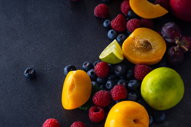 istock Creative flatlay with fresh fruits and berries on dark background with copy space. Grapes, blueberries, raspberries with peaches and lime 1140137945