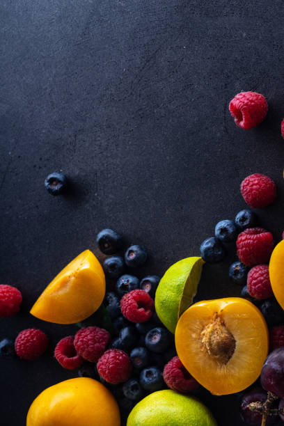 istock Creative flatlay with fresh fruits and berries on dark background with copy space. Grapes, blueberries, raspberries with peaches and lime 1140137954