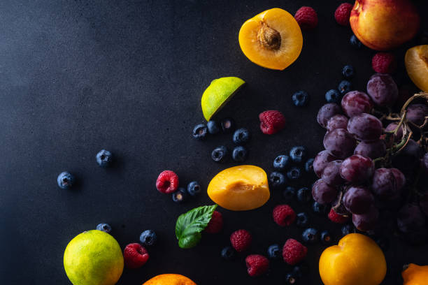 istock Creative flatlay with fresh fruits and berries on dark background with copy space. Grapes, blueberries, raspberries with peaches and lime 1140137962