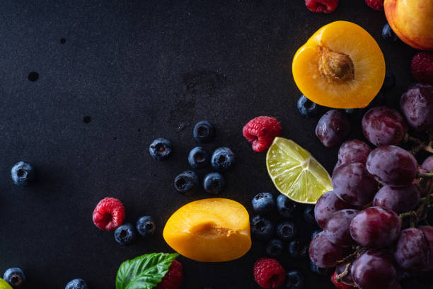 istock Creative flatlay with fresh fruits and berries on dark background with copy space. Grapes, blueberries, raspberries with peaches and lime 1140137964
