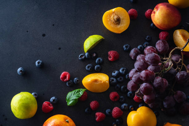 istock Creative flatlay with fresh fruits and berries on dark background with copy space. Grapes, blueberries, raspberries with peaches and lime 1140137968