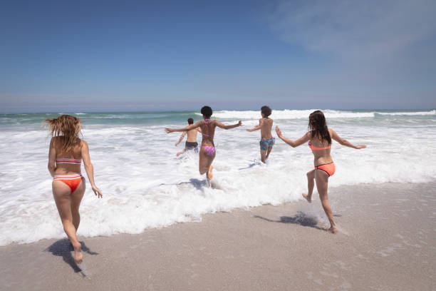 istock Group of friends running in ocean waves 1140139063