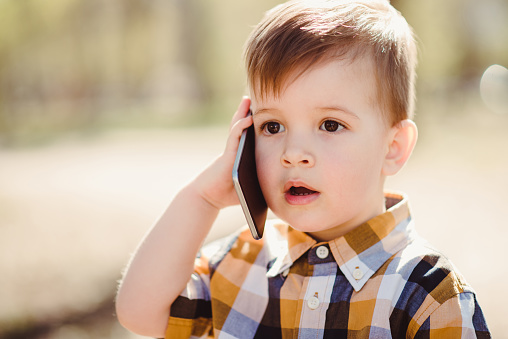 little boy speaks on the smartphone in the park