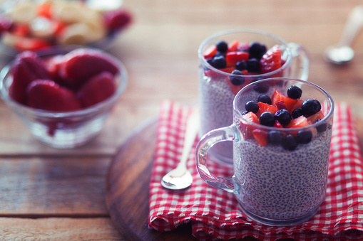 Chia pudding with strawberries and chokeberry, served in glasses, close-up