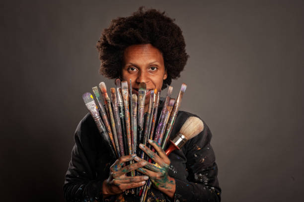 istock woman holding paintbrushes 1140140585