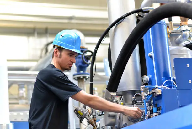 operator repairs a machine in an industrial plant with tools - pneumatics and hydraulics