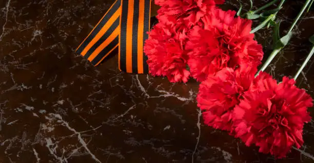 Photo of on the marble slab of the monument, there is a bouquet of carnations, St. George's ribbon and on the left there is a place for photos immortal regiment