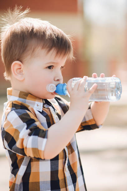 istock handsome boy drinks clear water from a bottle on a sunny day outside 1140143131